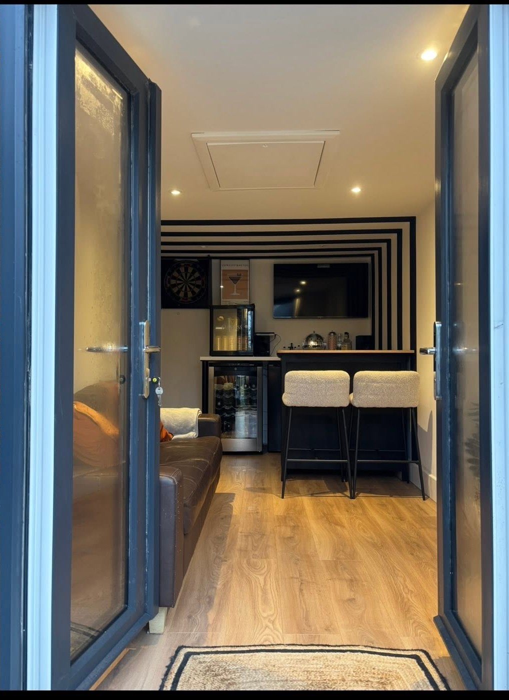 After: the finished garage conversion with a bar, wood floor and glazed doors in Northamptonshire by AC BRICKWORK & LANDSCAPING