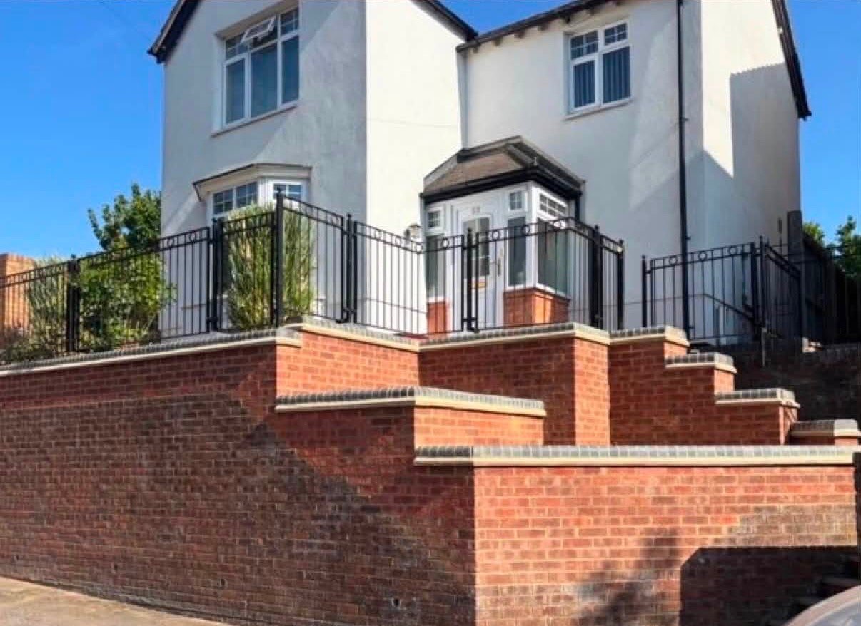 After: the rebuilt retaining wall and steps in new red brick with black railings in Northamptonshire by AC BRICKWORK & LANDSCAPING